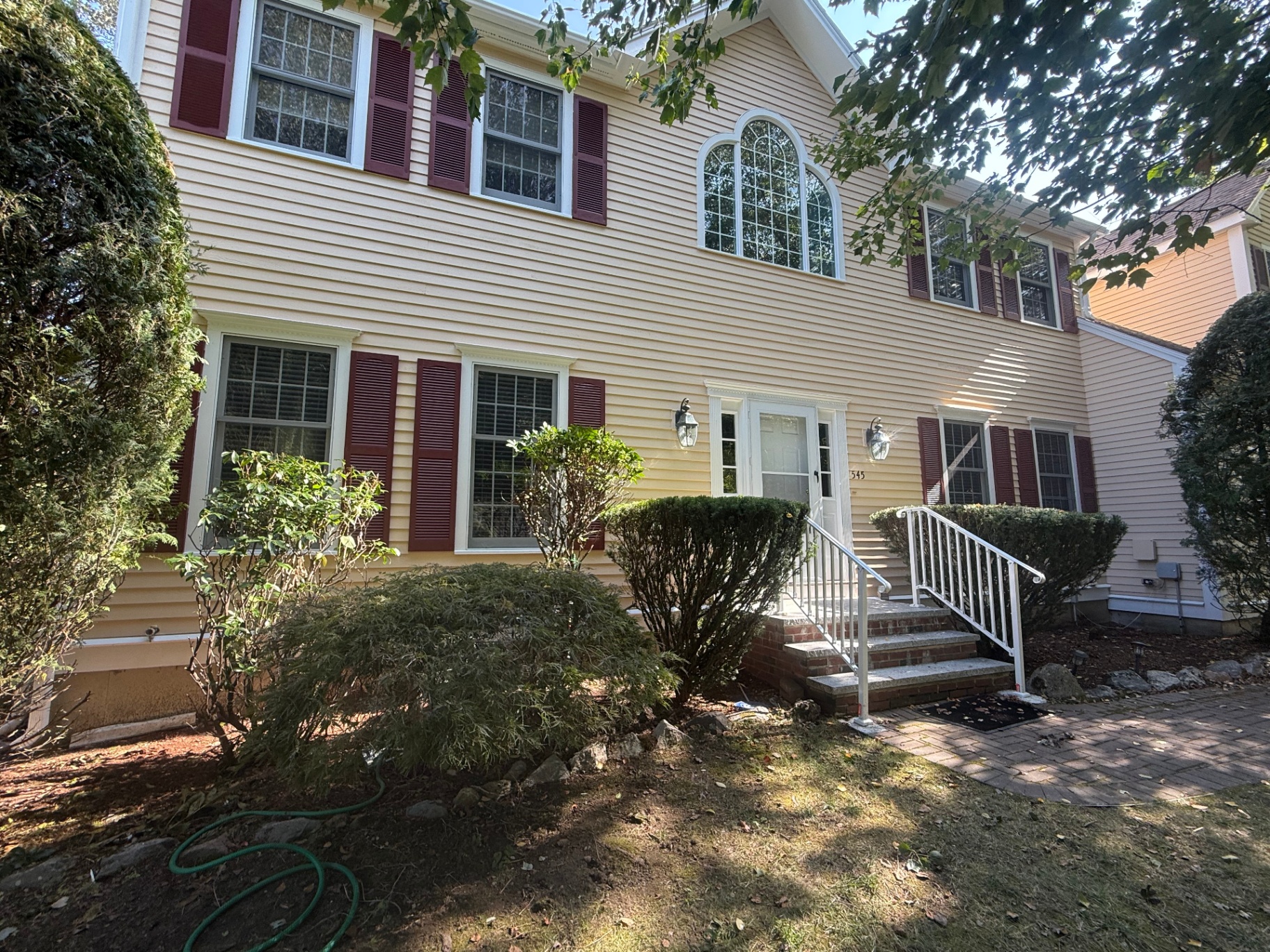 Colonial exterior repaint — soft yellow siding with burgundy shutters & crisp white trim