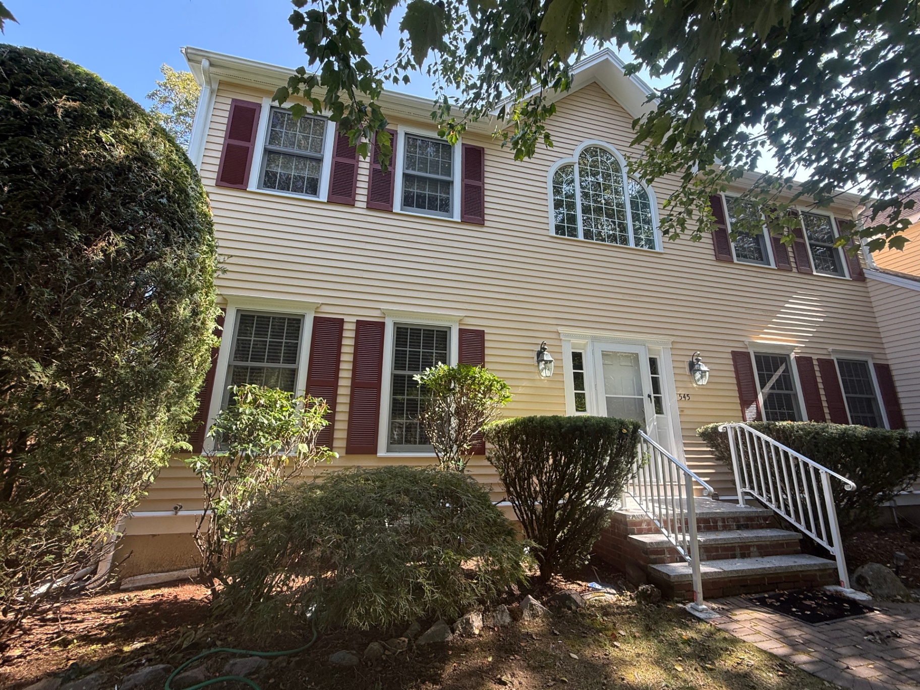 Colonial front elevation — freshly repainted siding, arched window & bold shutters